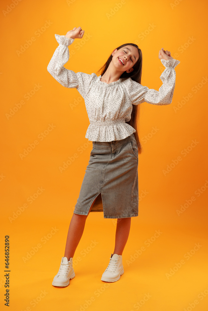 Portrait of a joyful happy teenage girl celebrating success on yellow background Portrait of a joyful happy teenage girl celebrating success on yellow background