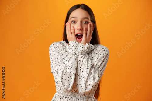 Fotografía Surprised amazed teen girl against yellow background in studio