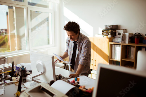 Young caucasian man going over paperwork while working in a media company office