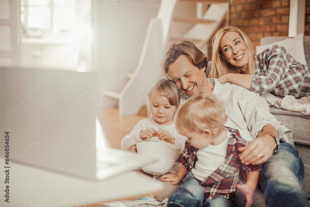 Young family watching a movie on the laptop together in the living room