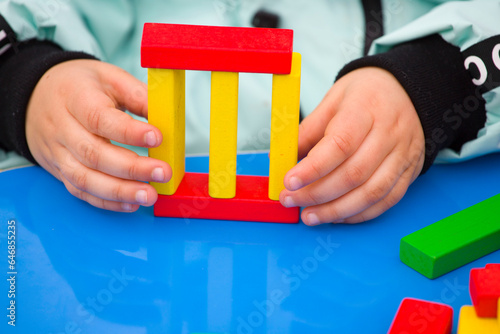 close-up of a child's hand playing wood blocks stack game