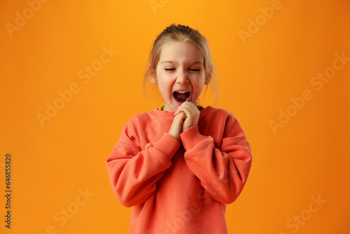 Little excited shocked girl against yellow background