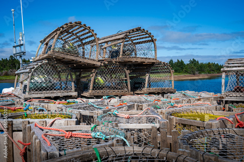 Leaning stack of atlantic lobster traps at the pier on a summer day, waiting for the next fishing season, Nova Scotia Canada photo