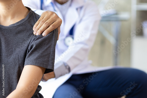 Doctor examining woman back pain in examination room. Doctor practicing back and shoulder physiotherapy for female patient in hospital. © Wasan