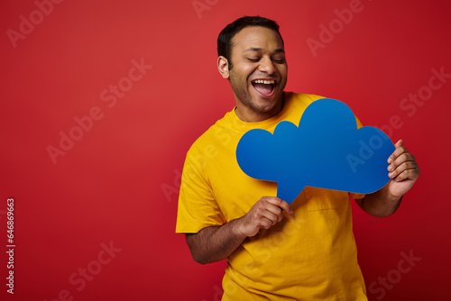 excited man in yellow t-shirt looking at blank thought bubble on red backdrop, cheerful face © LIGHTFIELD STUDIOS