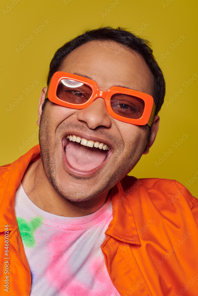 self-expression concept, excited indian man in orange sunglasses smiling on yellow backdrop self-expression concept, excited indian man in orange sunglasses smiling on yellow backdrop