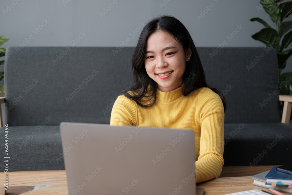 Young business freelance Asian woman working on laptop checking social media while lying on the sofa when relax in living room at home. Young business freelance Asian woman working on laptop checking social media while lying on the sofa when relax in living room at home.