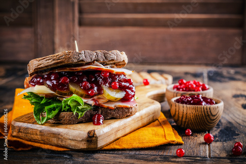 Homemade leftover thanksgiving day sandwich with turkey, cranberry sauce and vegetables. Dark rustic style