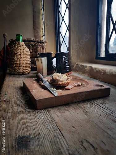 Scraps of food on a wooden plate, sit on a table by a castle window.