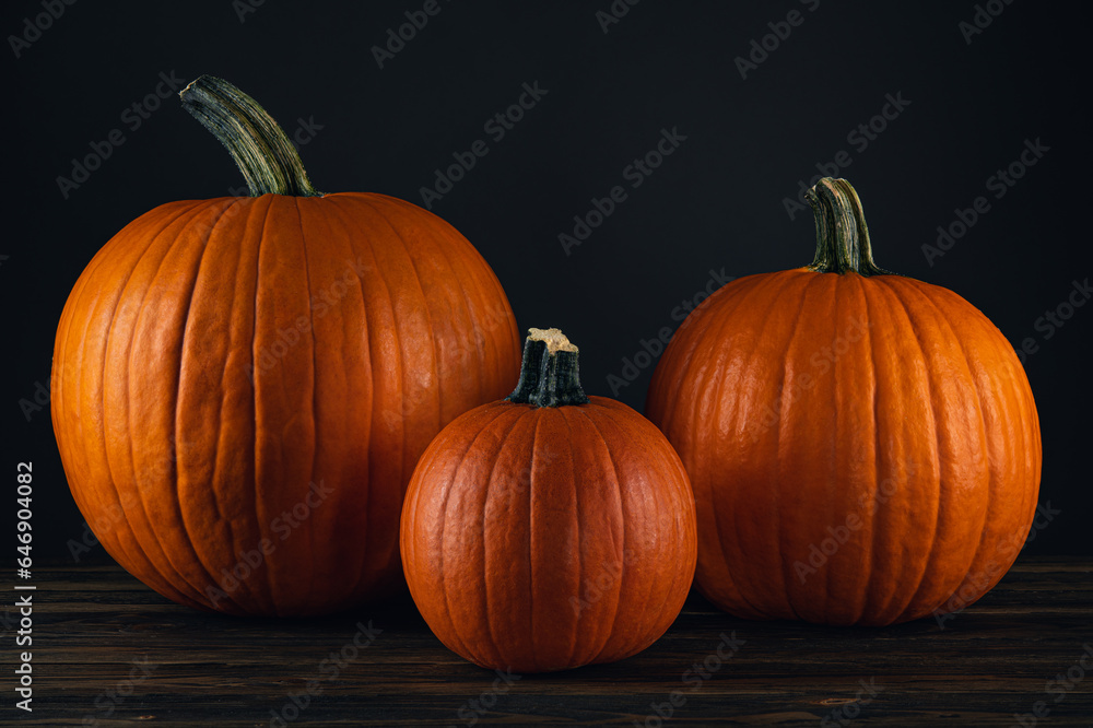 Pumpkin. Large and small pumpkins on natural wooden table. Pumpkin good for carving a Jack o Lantern on Halloween. Farm autumn October harvest. Dark scary atmospheric background. Mystery wallpaper Pumpkin. Large and small pumpkins on natural wooden table. Pumpkin good for carving a Jack o Lantern on Halloween. Farm autumn October harvest. Dark scary atmospheric background. Mystery wallpaper