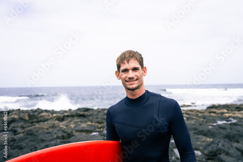 happy surfer in the coast with his red surf board