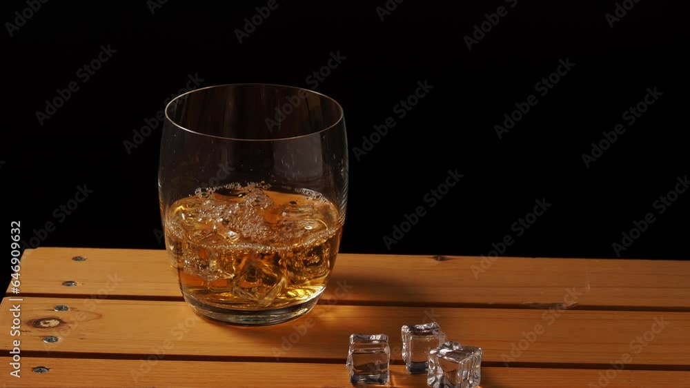 Glass of whiskey with ice on a wooden table. Whiskey with ice close-up. Glass of whiskey with ice on a wooden table. Whiskey with ice close-up.