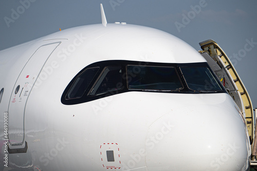 Detailed view of commercial aircraft nose and windshield. Boarding airplane on airport runway.