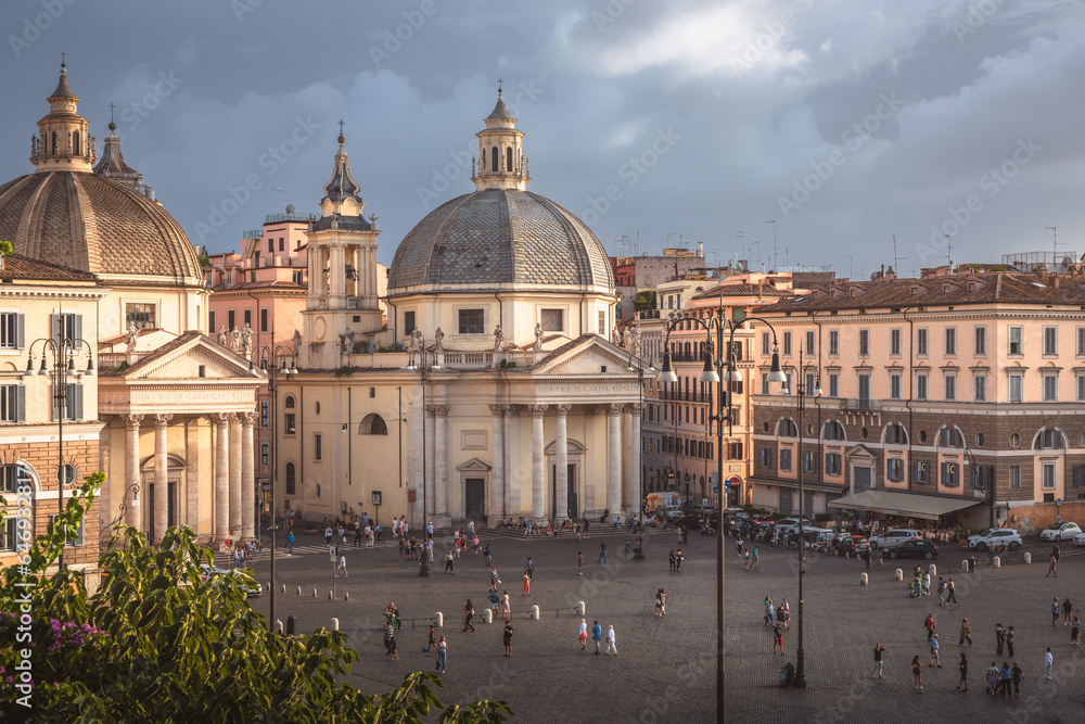 Moody, atmospheric cityscape view over Baroque churches and obelisk in the popular tourist landmark Piazza del Popolo in the historic old town.