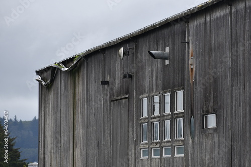 Old wooden building with many vents sticking out of siding.