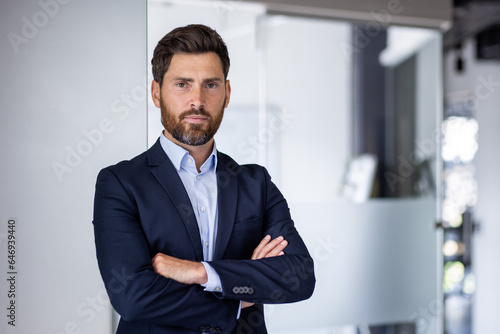 Portrait of mature experienced financier businessman, man thinking seriously looking at camera with crossed arms, confident investor banker inside office workplace in business suit photo