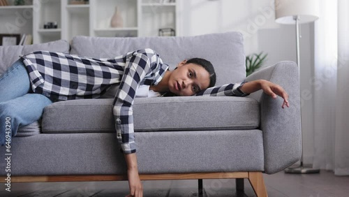 Tired african american girl slumps on couch feeling lethargic. Feeling depressed, lack of motivation, sadness, boredom. Exhausted, she collapses on the couch from stress. Burn out.