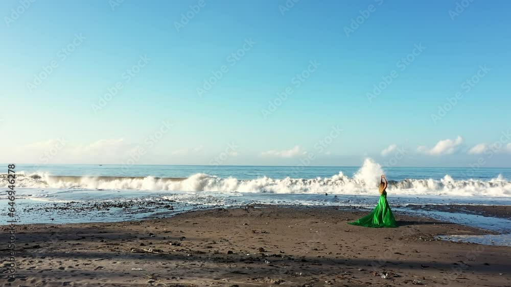Girl in a long dress running on a black beach in Bali. Big waves in the ocean. Girl in a long dress running on a black beach in Bali. Big waves in the ocean.