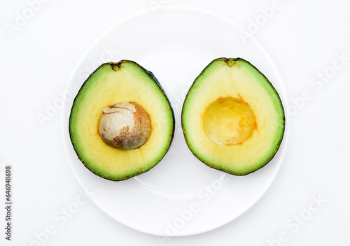 Sliced green avocado on a white background. Pieces of green vegetable on a white plate. Delicious food for a vegan.