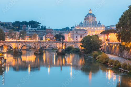 Sceninc twilight view of Saint Peter's Basilica at Vatican City and Ponte Vittorio Emanuele II illuminated along the Tiber River on a summer evening in Rome, Italy. photo