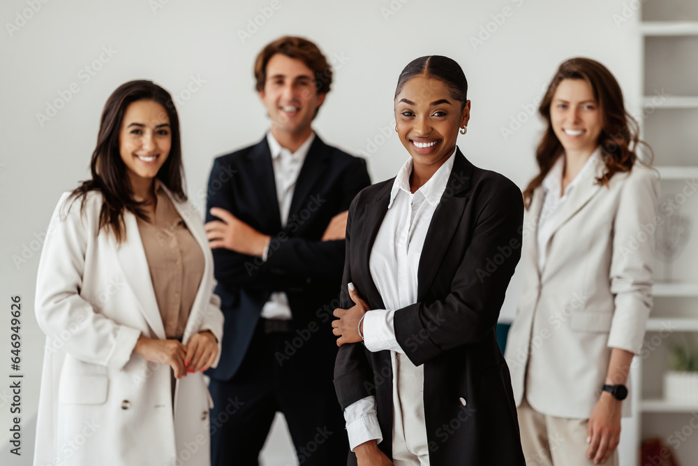 Successful multiracial business team with black female leader standing in office and smiling at camera Successful multiracial business team with black female leader standing in office and smiling at camera