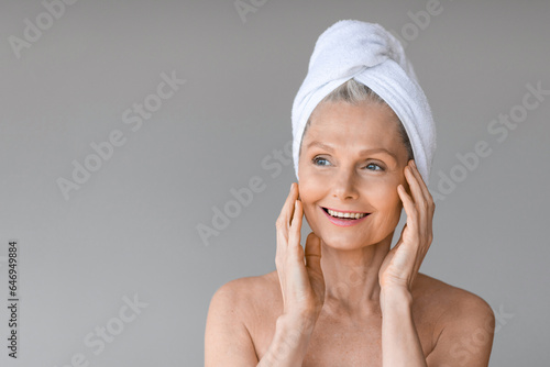 Beauty and skincare. Portrait of beautiful mature woman with towel on head, looking aside at free space and smiling