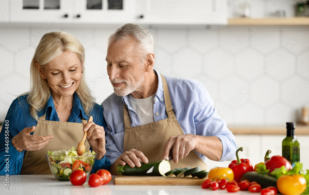 Happy senior couple preparing healthy salad together in kitchen interior Happy senior couple preparing healthy salad together in kitchen interior