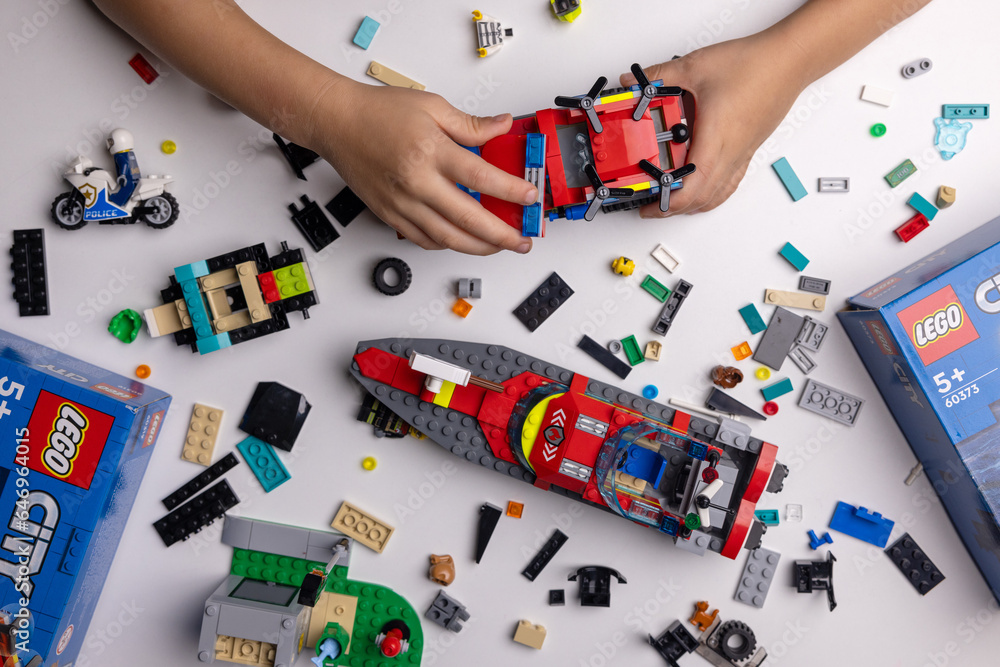 Naklejka premium Riga, Latvia - September 12, 2023: child playing with Lego constructor on the table. building a firefighter car