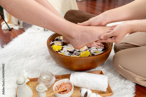 Woman indulges in blissful foot massage at luxurious spa salon while masseur give reflexology therapy in gentle day light ambiance resort or hotel foot spa. Quiescent