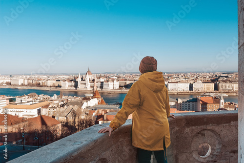 Rear view of a girl in a yellow jacket, in the background the panorama of Budapest.