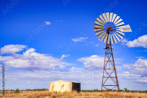 Fényképezés Windmill in Queensland, Australia, with blue sky and fluffy white clouds