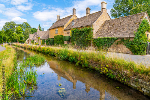 A picturesque row of stone homes along the River Eye in the idyllic country village of Lower Slaughter, in the Cotswold District of Gloucestershire, England, UK. photo