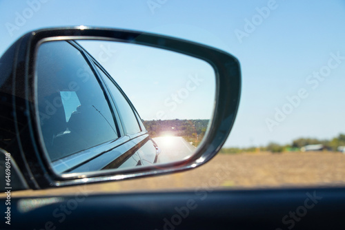 Looking in the rear view mirror in a moving car along the highway in Ukraine in the summer on vacation during the day, road