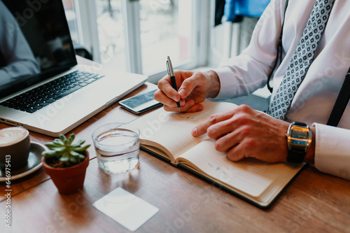 High angle shot of a man writing notes in his notebook while sitting in a cafe.