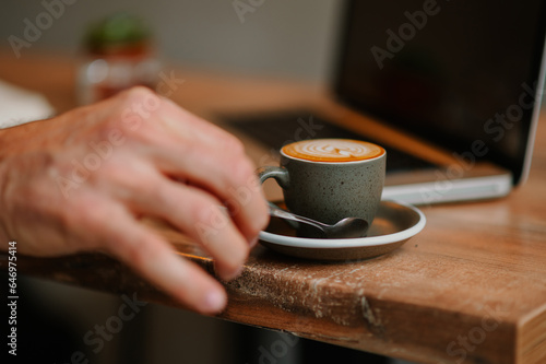 Man's hand lifting up a coffee spoon from the tray with a full cup of coffee. © Zamrznuti tonovi