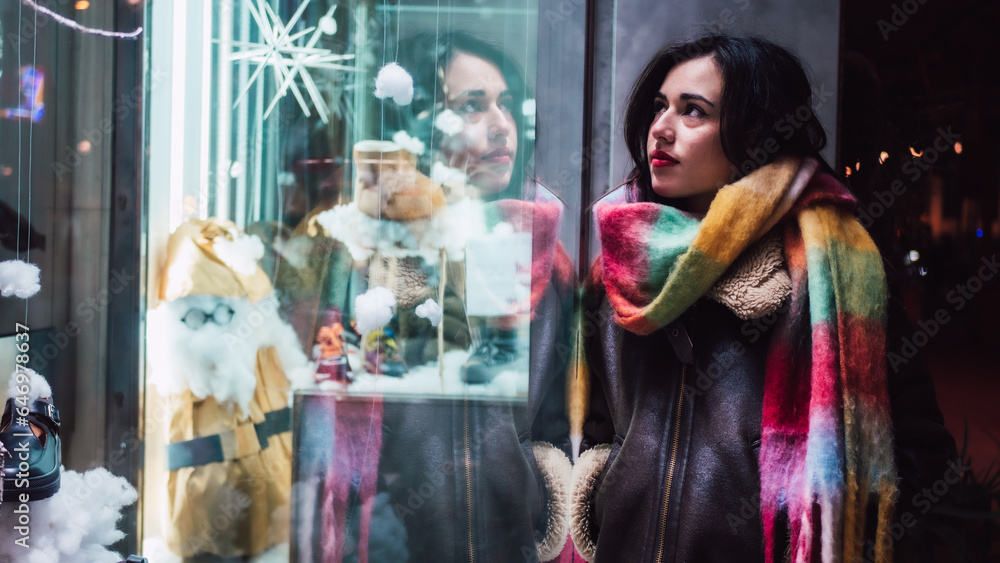 Fototapeta premium Pretty girl with a scarf looking at Christmas stores