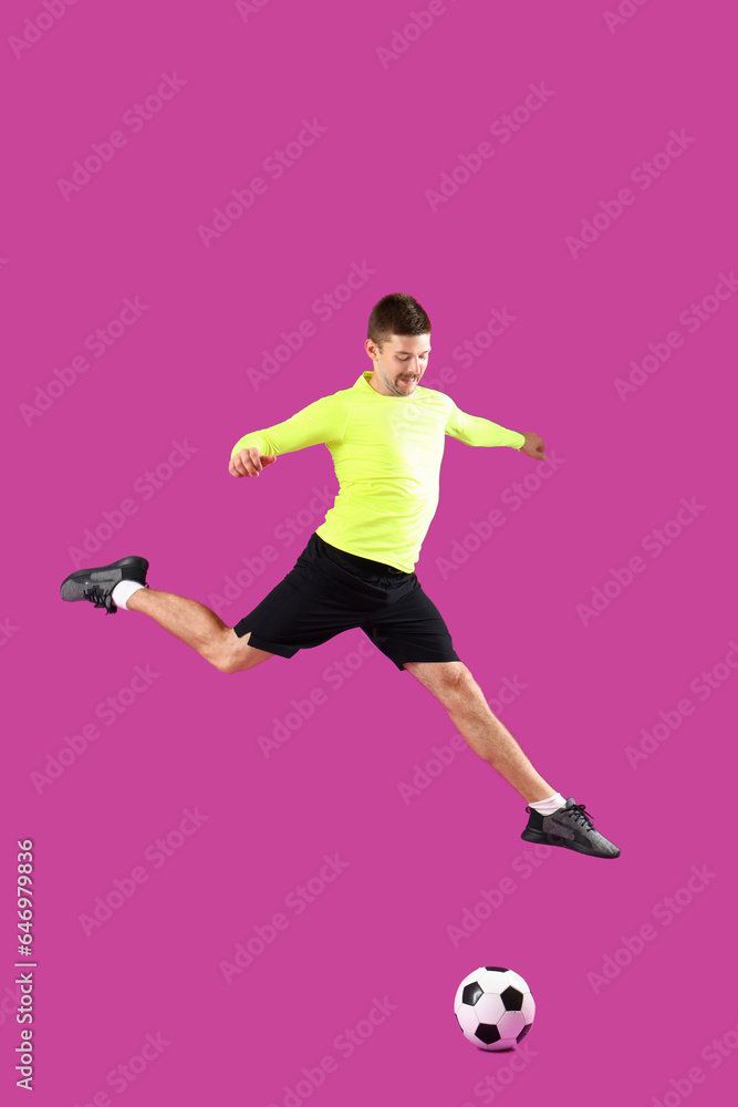 Fototapeta premium Jumping soccer player on magenta background