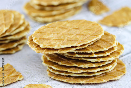 Butter waffle cookies stacked on a grey background. Waffle crisps close-up. Tasty home made thin waffles. Sweet food concept