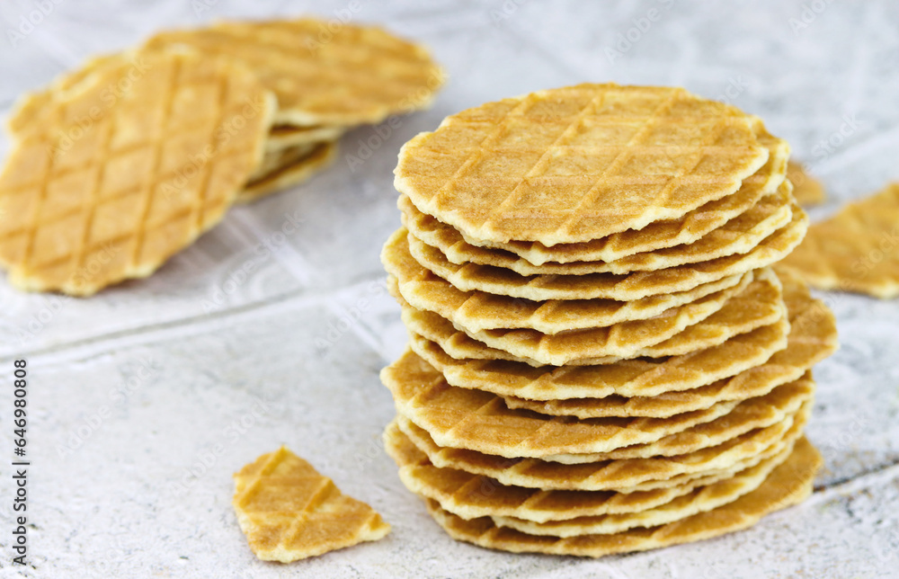 Thin waffles. Stack of home made butter waffle cookies on a grey background. Waffle crisps close-up. Sweet food concept Thin waffles. Stack of home made butter waffle cookies on a grey background. Waffle crisps close-up. Sweet food concept