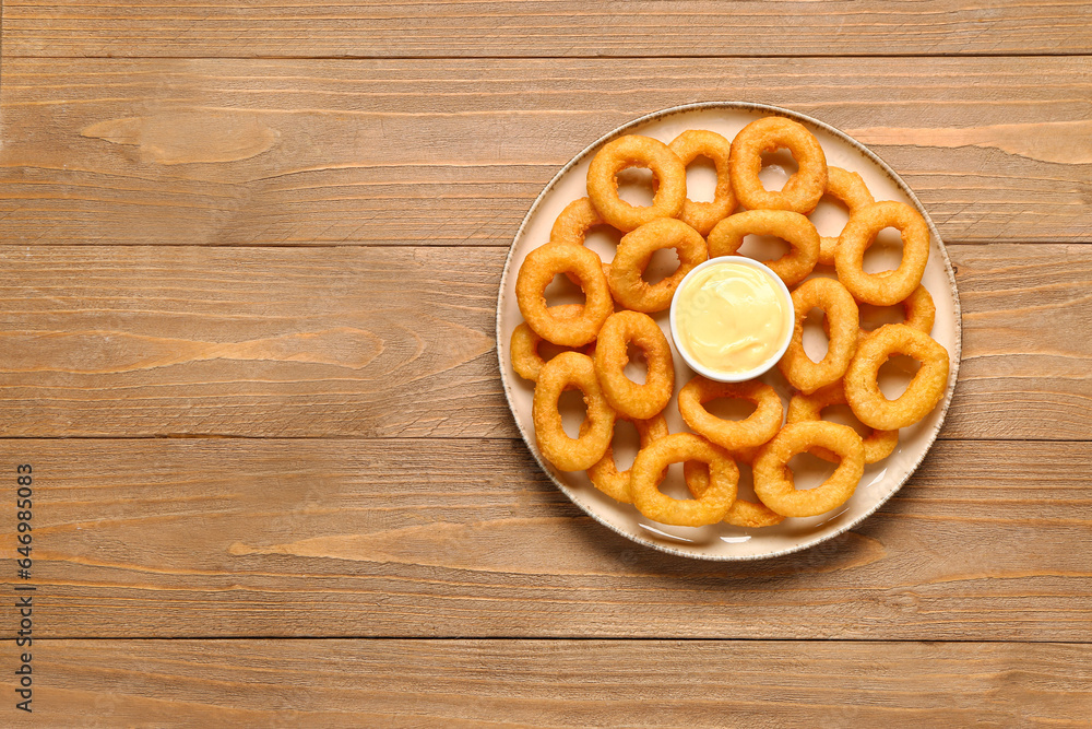 Plate with fried breaded onion rings and mayonnaise on wooden background Plate with fried breaded onion rings and mayonnaise on wooden background