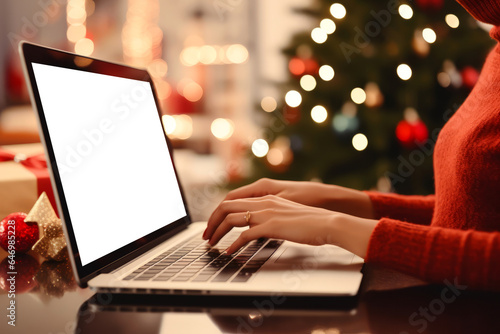 Woman wearing red sweater using laptop with blank white background on christmas tree background with space for your text or inscriptions, online christmas gift shopping concept.generative ai

