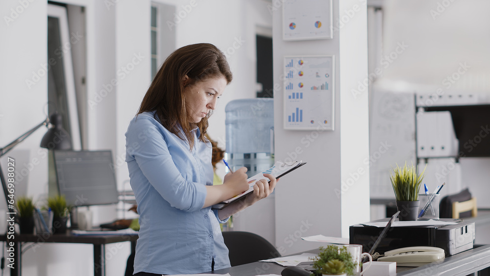 Business manager writing data analytics on papers, working with professional corporate report to increase profit. Young woman taking notes on files for investment plan development. Business manager writing data analytics on papers, working with professional corporate report to increase profit. Young woman taking notes on files for investment plan development.