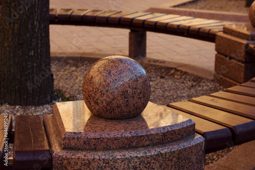 red granite decoraton near modern wooden bench in the city center photo