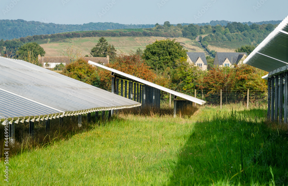 Solar Farm panels,and rural residential buildings in the near distance, the Cotswolds, Gloucestershire,England,United Kingdom. Solar Farm panels,and rural residential buildings in the near distance, the Cotswolds, Gloucestershire,England,United Kingdom.