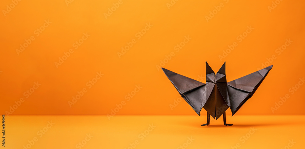 Halloween Themed Paper Origami Bat Against an Orange Background Banner with Copyspace