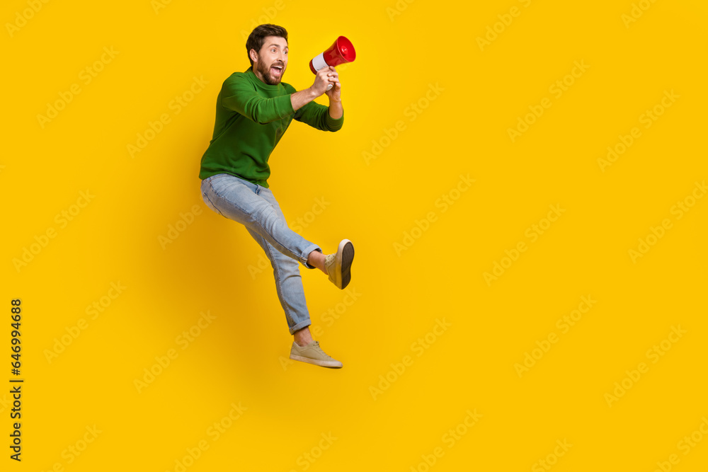 Full length photo of young screaming man hold announce strike against low salaries manufacture problems isolated on yellow color background