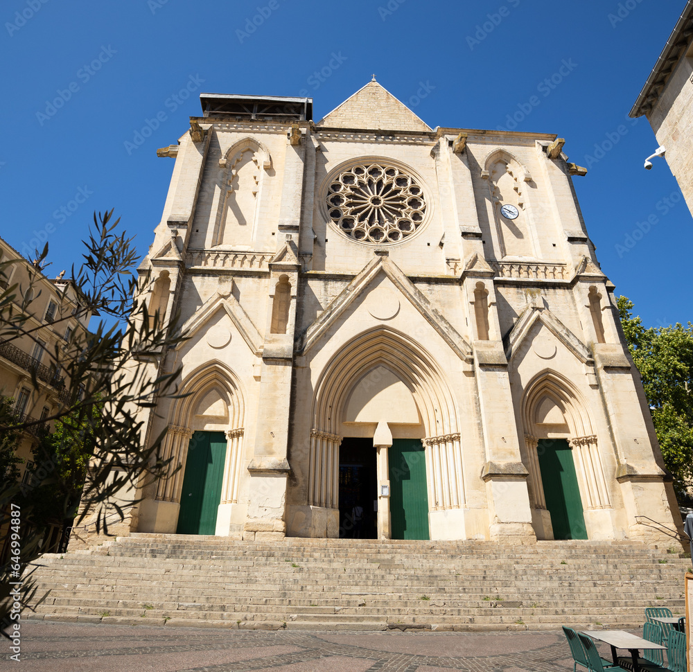 Building of neogothic church of Saint-Roche-de-Montpellier, made of white limestone, stands out in contrast against clear blue sky. Bottom view