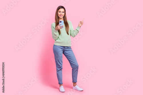 Full length body photo of attractive nice famous tik tok vlogger woman direct finger empty space ads isolated on pink color background © deagreez