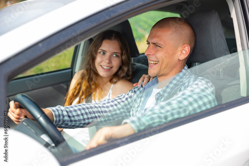Attractive young woman and man talking and smiling in car during common trip © JackF