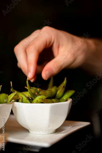 Hand reaching for edamame 